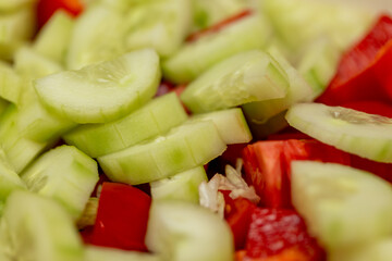 Extreme close-up of fresh sliced cucumbers and red bell peppers. Vibrant, healthy ingredients for a vegetarian salad. Food background with selective focus and beautiful bokeh.