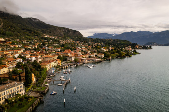 Aerial view of a charming coastal town where terracotta rooftops meet the deep blue waters, nestled against a backdrop of verdant hills, Azzano, Lombardy, Italy.