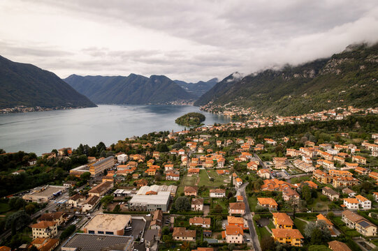 Aerial view of terracotta rooftops nestled amidst the verdant landscape where the tranquil lake meets the soaring mountains, Lenno, Lombardy, Italy.