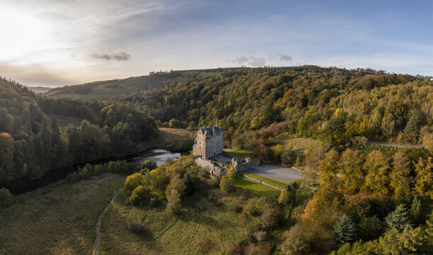 Aerial view of the historic Neidpath Castle standing proudly amidst the autumnal hues of the surrounding forest, where the River Tweed meanders serenely, Peebles, Scotland, United Kingdom.
