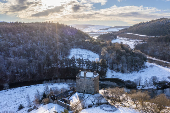 Aerial view of the stark silhouette of Neidpath Castle cutting through the snowy landscape, a wintery scene of Scotland's historic beauty, Peebles, Scotland, United Kingdom.
