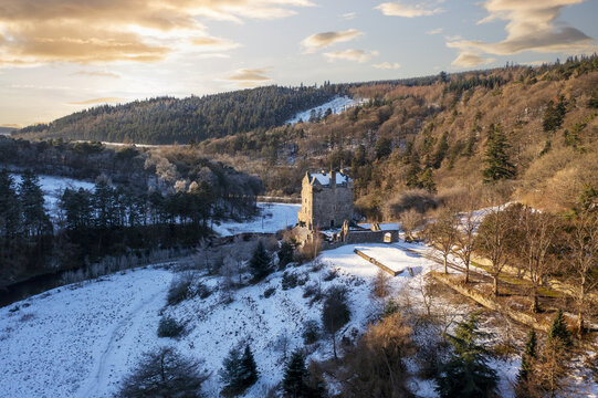 Aerial view of Neidpath Castle standing proudly amidst a snow-dusted landscape, its ancient stones contrasting with the soft, white blanket, Peebles, Scotland, United Kingdom.