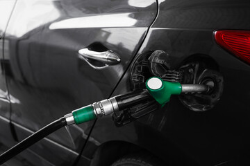 Refueling nozzle in modern car's fuel tank at gas station, closeup