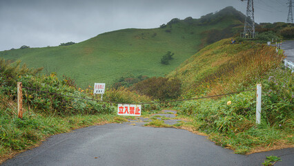 Muroran, Hokkaido, Japan - Oct 4 2024, panoramic view of a country paved road passing through forests and fields, without cars and without people, in cloudy weather, at daytime, Muroran, Japan