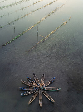 Aerial view of boats clustered in a circular pattern on the water's surface, surrounded by parallel lines of structures,Tuy An, Phu Yen, Vietnam