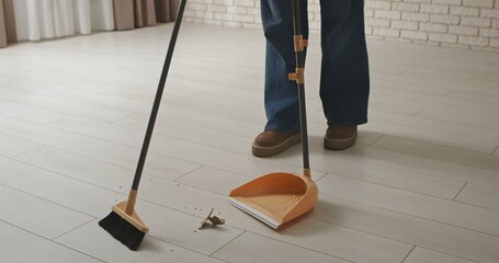 Person Sweeping Clean Floor with Broom and Dustpan