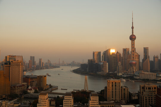 View of a cityscape bathed in the warm glow of sunset, highlighting the river and iconic Oriental Pearl Tower, Shanghai, Shanghai, China.