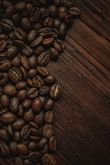 Roasted arabica coffee beans forming a diagonal line on dark brown wooden planks, creating rich texture and a natural background