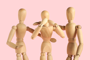 Wooden mannequins hugging on pink background