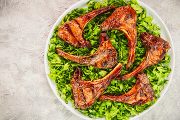 Middle Eastern traditional dish with grilled juicy lamb chops/ribs placed on bed of fresh chopped parsley. Top view with copy space.