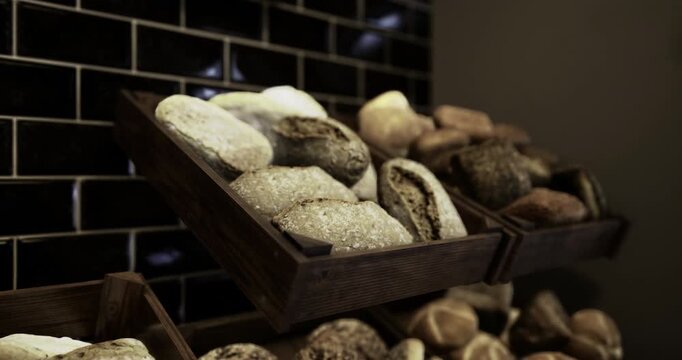 An assortment of fresh, artisanal breads is neatly arranged on wooden shelves in a cozy bakery. The warm atmosphere highlights the textures and colors of the baked goods.