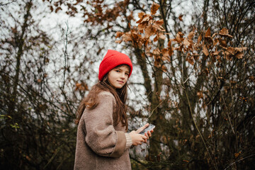 Naklejka premium Young girl standing in nature wearing red hat.
