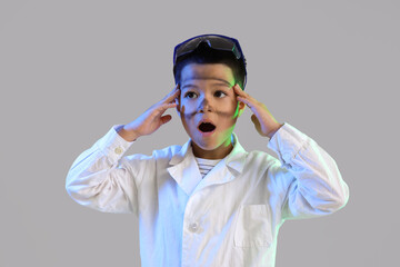 Surprised little boy with dirty face after explosion during chemistry experiment on grey background