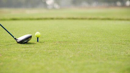 Golf ball on tee with driver on fairway.