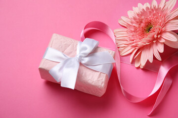 Composition with figure 8 made of ribbon, gerbera flower and gift box on pink background. International Women's Day celebration