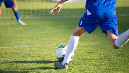 Football player dribbling ball on grassy field.