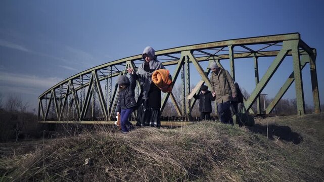 An immigrant family travels by walking on alternative paths through the rural area on a cold sunny day in the winter season
