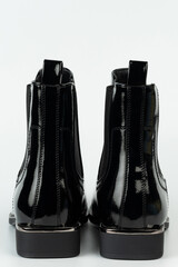 Black patent leather boots displayed on a white background