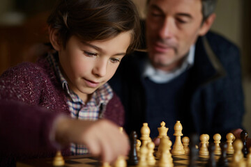 A tender moment between a father and son as they play chess, illustrating familial bonds, strategic thinking, and the joy of learning through play and interaction.