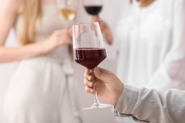 Female hand with glass of exquisite red wine on light background