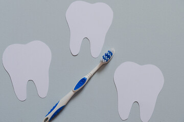 Toothbrush next to paper teeth, top view, flat design for dentist's day greeting card