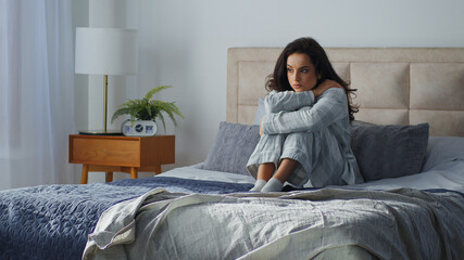 Caucasian woman thinking hugging knees on bed depression unhappy morning feeling sad upset in home bedroom girl female think melancholy feel resting relaxing wake up pondering problem mental trouble