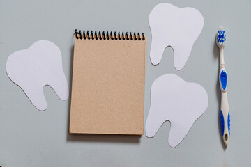 teeth next to a toothbrush and a notebook, reminder of dentist day