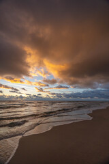 Storm clouds over ocean shoreline at sunrise, vertical