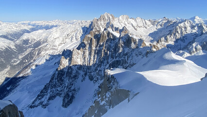Naklejka premium High altitude winter alpine mountain landscape with snow covered peaks, glaciers and rugged ridges. Clean natural scenery suitable for travel, outdoor, environment and background use.