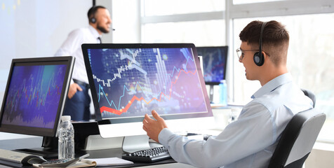 Male trader with headset working at table in office, back view