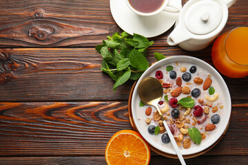 Healthy breakfast. Oatmeal with nuts, berries and milk in bowl served on wooden table, flat lay. Space for text