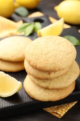 Tasty lemon cookies and fruit slices on dark wooden table, closeup