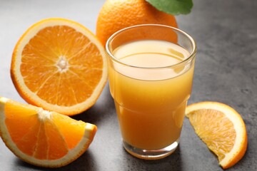 Fresh orange juice and fruits on grey table, closeup