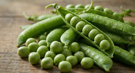 Fresh green peas and open pods on a rustic wooden table with water droplets for healthy food concept and natural produce