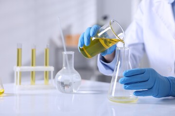 Scientist checking motor oil quality at table in laboratory, closeup