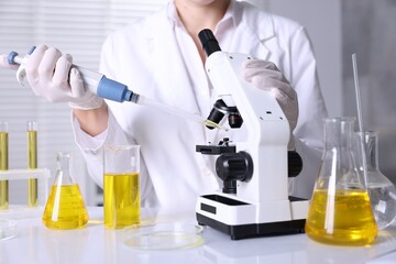 Scientist checking motor oil quality at table in laboratory, closeup