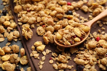 Tasty granola with dried fruits and spoon on black table, closeup