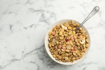 Tasty granola with dried fruits and nuts in bowl on white marble table, top view. Space for text
