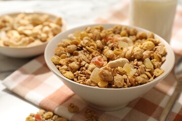 Tasty granola with dried fruits and nuts in bowl on white table, closeup