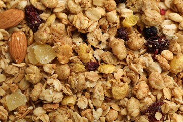Tasty granola with dried fruits and nuts as background, top view