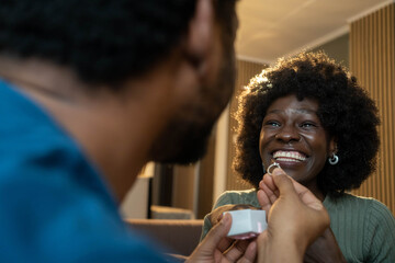 Black man proposing to happy woman at home, close-up romantic moment