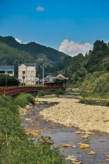 Fototapeta premium Traditional Chinese Bridge Crossing River in Green Mountain Valley Village