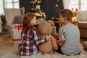 Rear view of siblings opening christmas presents in pajamas.