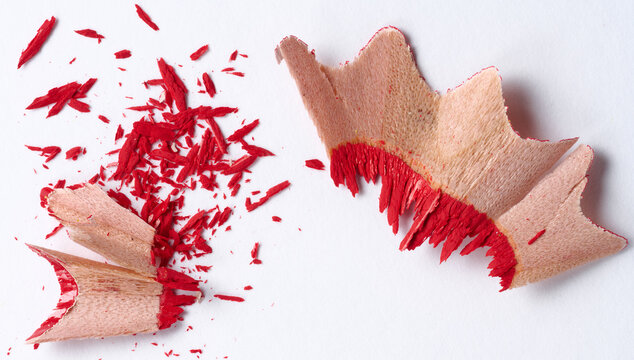 Wooden red shavings of lead pencil on white background, top view