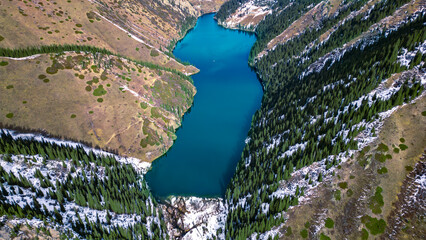 Aerial View of Turquoise Mountain Lake Between Steep Forested Slopes