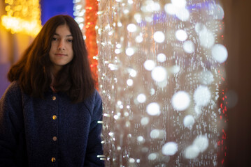 Portrait of a Twelve-Year-Old Teenage Girl Smiling at the Camera Beside Christmas Lights on a European Winter Night