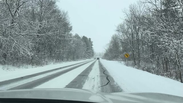 Driving down a country road during a snow storm. Driver point of view. 