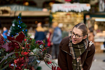 Cheerful young woman looking for New Year decorations in traditional street market