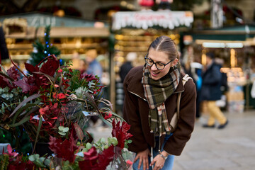 Cheerful young woman looking for New Year decorations in traditional street market
