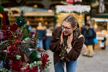 Cheerful young woman looking for New Year decorations in traditional street market